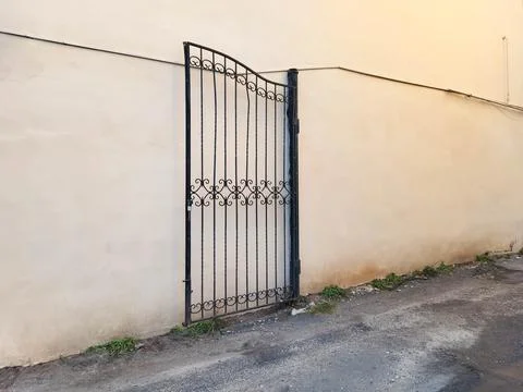 A wrought-iron gate leaf on the background of a beige house wall. Foto stock