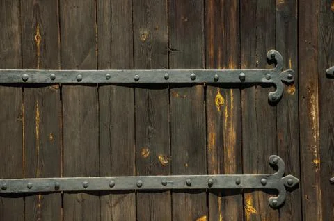 Wrought iron hinge with studs in an old wooden door Stock Photos
