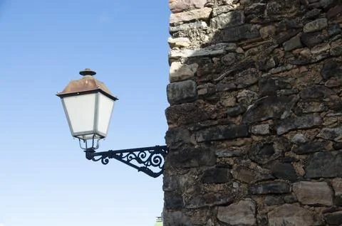 Wrought iron lamppost on stone wall Stock Photos