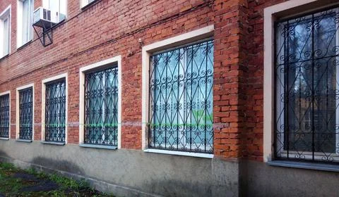 Wrought iron patterned grilles are installed outside on the first floor windows Stock Photos
