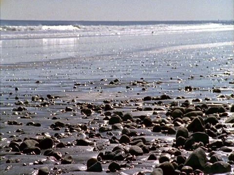 WS rocks in wet sand in foreground, waves rolling in to shore Stock Footage 86750608