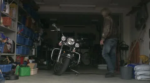 WS Senior man leaving garage on Harley Davidson Stock Footage