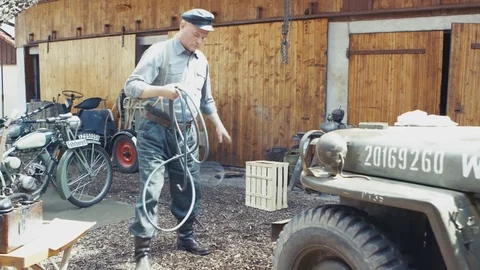 WW2 – A german worker preparing hoses connected to a air compressor Stock Footage