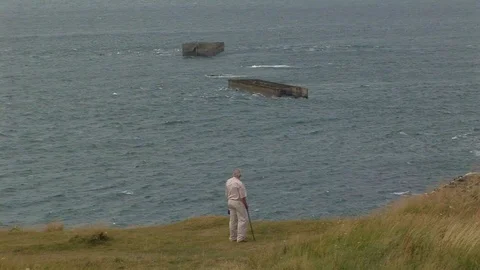 WWII Veteran looking at remnants of Phoenix blocks Normandy, France Stock Footage 101264262