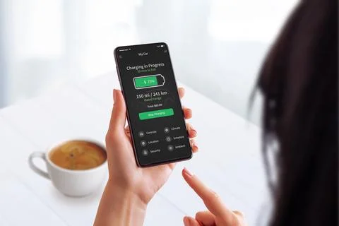 Wwoman enjoys coffee while checking her EV charging status Stock Photos