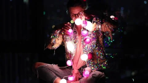 Wwoman wearing glowing jacket with sequins is holding light balls in her hands. Stock Footage 233500413