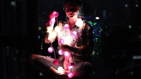 Wwoman wearing glowing jacket with sequins is holding light balls in her hands. Stock Footage 233500545