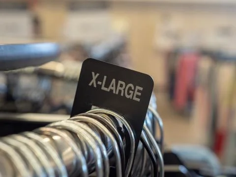 X-large extra large clothes section sign on steel hanging rack with hangers in Stock Photos