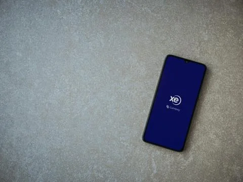 XE Currency app launch screen with logo on the display of a black mobile smar Stock Photos