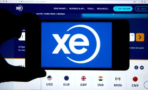 Xe.com logo and application on a cell phone over an official web site Stockfoto's