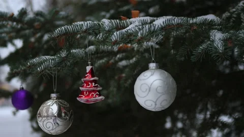 Xmas balls and red herringbone hangs on Christmas tree under snowfal, slow-mo Stock Footage 223035467