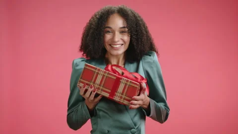 Xmas box falling into hands of cheerful young dark-haired beauty in silk dress Stock Footage 257114163