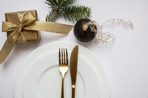 Xmas dinner table setting, Gold gift box and cutlery on white set of dishes, Stock Photos