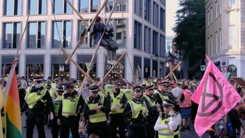 XR Protesters dance around rebels in bamboo structures surrounded by police Stock Footage 160151147