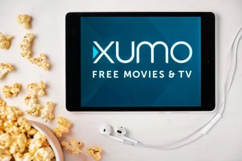 Xumo on the screen of the tablet with popcorn box and Apple earphones on the Stock Photos