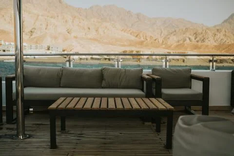 Yacht deck featuring comfortable seating with a scenic mountain and sea backdrop 库存照片