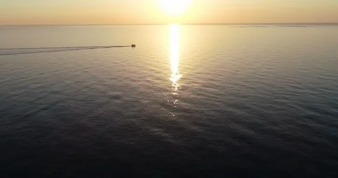 Yacht sailing over serene sea near the sun in an orange sunrise Stock Footage 124223353