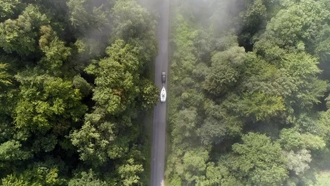 Yachting boat on trailer pulled by car on winding mountain road - drone aerial Stock Footage 99588083