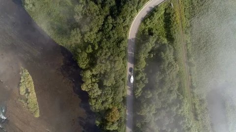Yachting boat on trailer pulled by car on winding mountain road - drone aerial Stock Footage 99597891