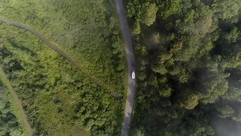 Yachting boat on trailer pulled by car on winding mountain road - drone aerial Stock Footage 99603195