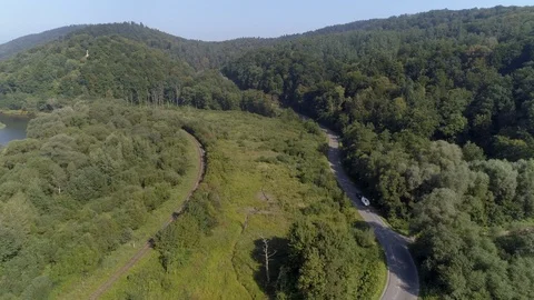 Yachting boat on trailer pulled by car on winding mountain road - drone aerial Stock Footage 99614236