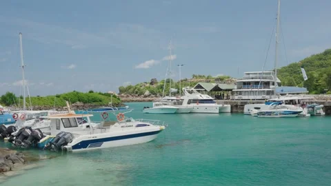 Yachts, catamarans, and boats float in turquoise harbor of La Digue on sunny day Видео 331506006