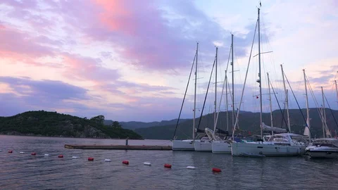 Yachts at the pier on the background of a mountain at sunset	 Stock Footage 127945200