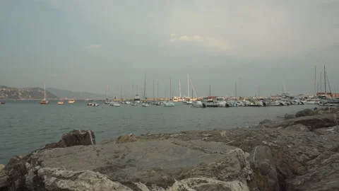 Yachts in Rapallo at summer sunset and rocks on the foreground, Italy - 4K Stock Footage 229725307