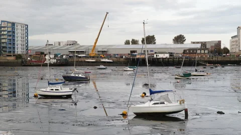 Yachts sitting in mud during low tide in Granton Harbour in Edinburgh, UK - 4K Stock Footage 253821464