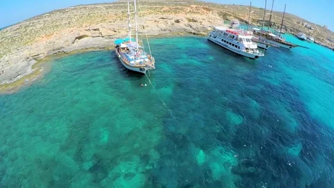 Yachts with tourists stand near a picturesque sea shore. Aerial view. Malta Stock Footage
