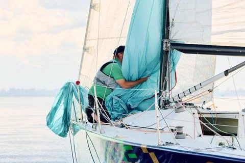 Yachtsman assembles a light thin sail spinnaker during sailing regatta in the Stock Photos