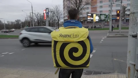 Yandex walking courier with a yellow backpack makes delivery around the city Stock-Footage 238848605