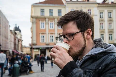 Yang man in glasses with beard drinks coffee Stock Photos