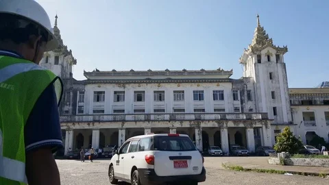 Yangon central train station building, car drives, workers in yellow vests walk Vídeos de archivo 78076063