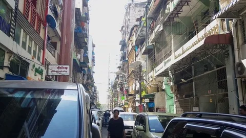 Yangon street, locals walk through traffic jam, satellite dishes, buildings Stock Footage