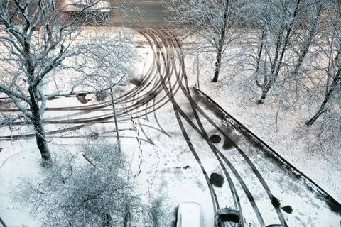 The yard is covered with the first snow, the traces of wheels and legs. View Stock Photos