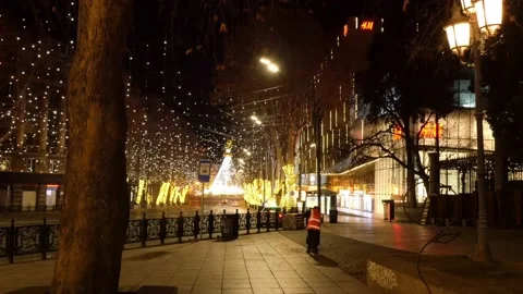 Yard-keeper sweeping out empty street with Christmas decorations 스톡 동영상 169378210