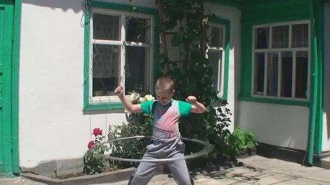 In the yard the school-age boy turns the Hoop Vídeos de archivo 75890768