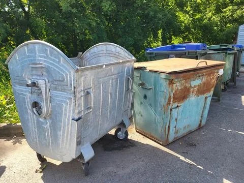 In the yard, there is a parking lot for garbage containers, surrounded by g.. Stock Photos