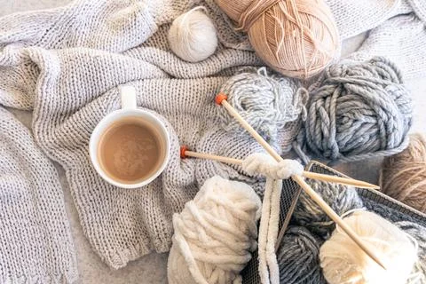 Yarn threads, knitted elements and a cup of coffee, top view. Stock Photos