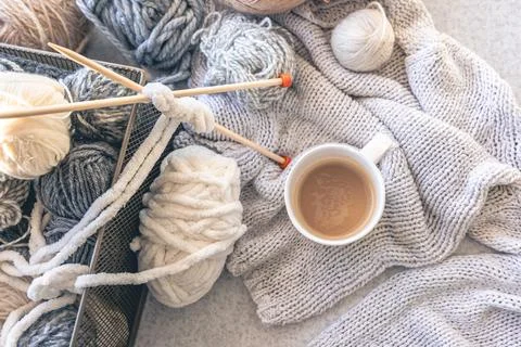 Yarn threads, knitted elements and a cup of coffee, top view. Stock Photos