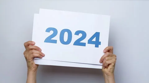 The year 2023 changes to 2024 on white paper in the hands of a woman. Stock Footage 249897874