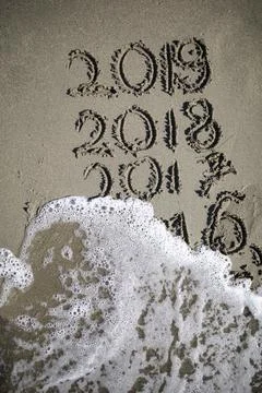 Years 2019 2018 2017 2016 written in sand, wave erasing the past Stock Photos