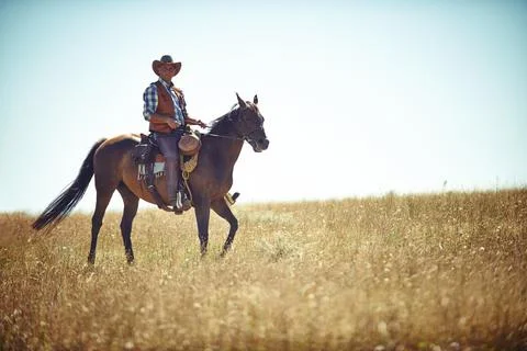 Yeeha. Full-length portrait of a mature man on a horse out in a field. Stock Photos