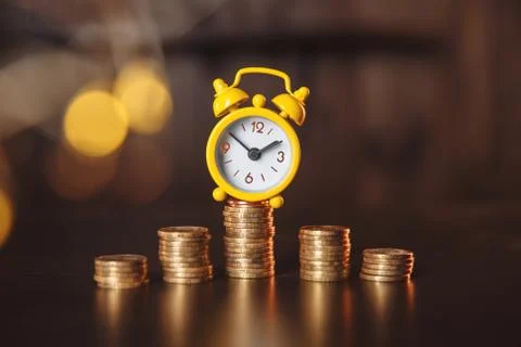 Yellow alarm clock and stack of coins with financial concept Fotos Stock
