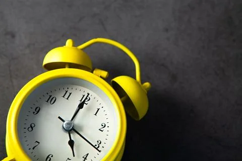 Yellow alarm clock on dark background. Time concept. Stock Photos