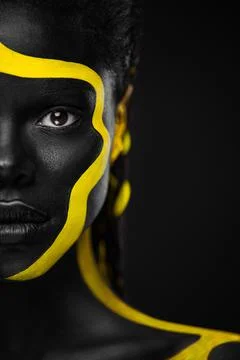 Yellow and black body paint. Woman with face art. Young girl with colorful Foto stock