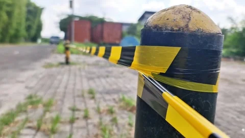 Yellow and Black Caution Tape on Bollard Marking Restricted Area at Empty Street Stock Footage 333507624