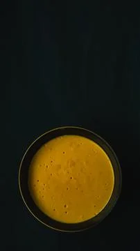 Yellow and black ceramic bowl filled with pumpkin puree on a black background Stock Photos