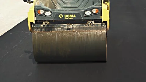 Yellow and black road-roller with large grey drum drives Stock Footage 134460853